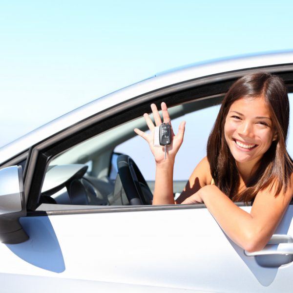 woman holding a key while inside her new car