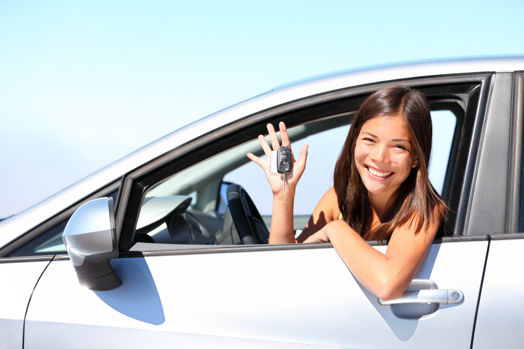 woman holding a key while inside her new car
