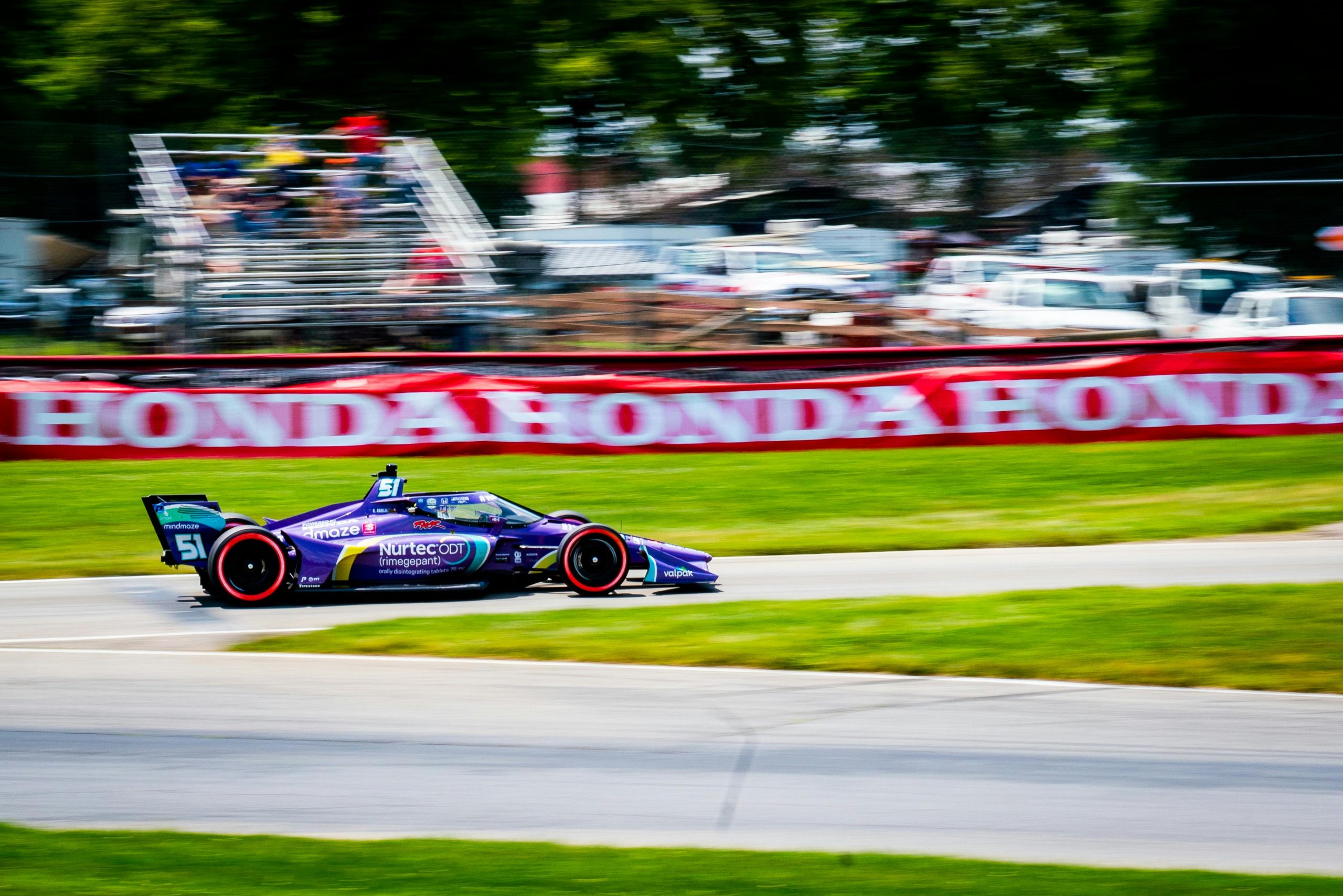 blue IndyCar race car speeding down a track