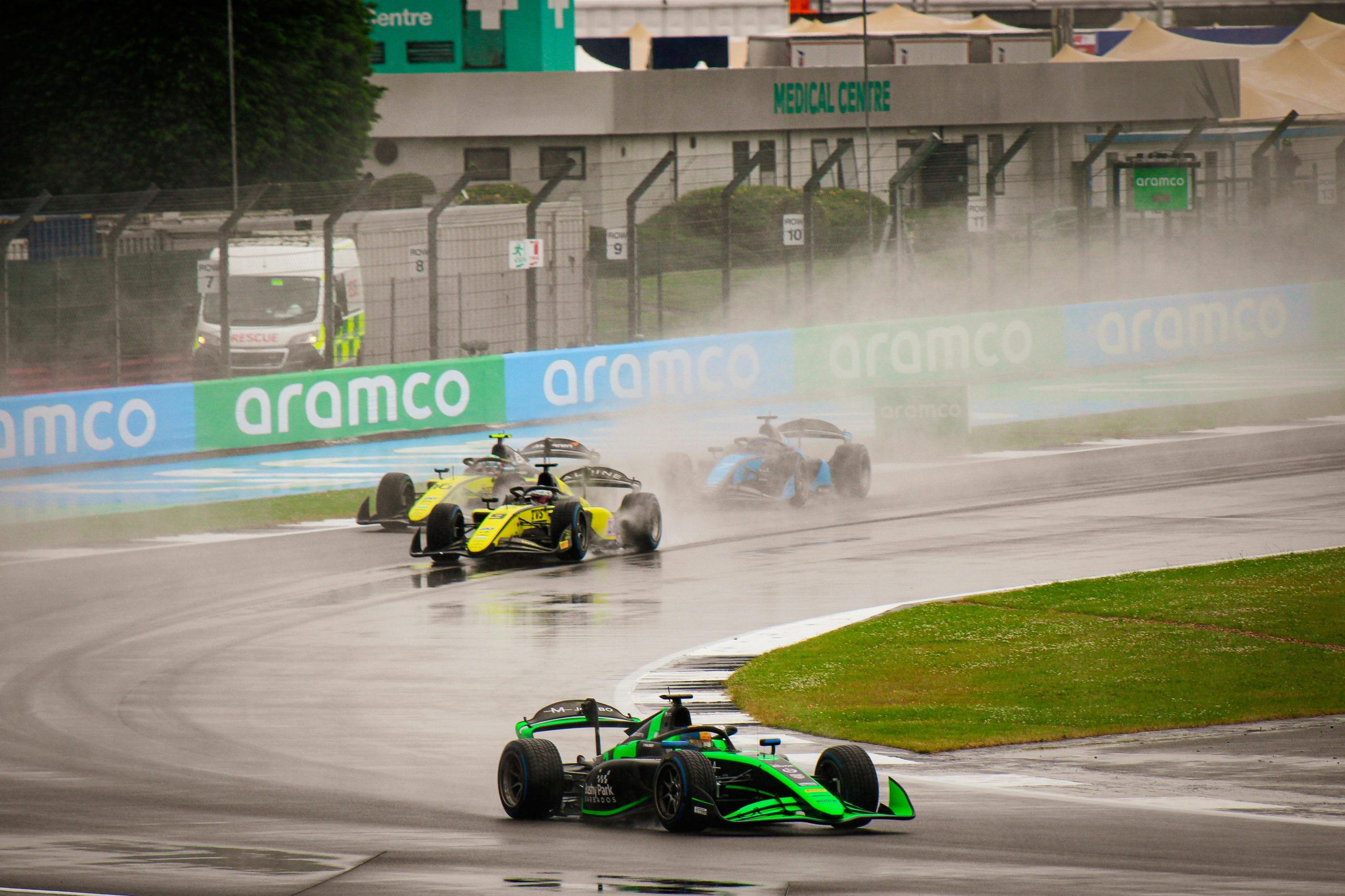 race cars speeding down a wet track